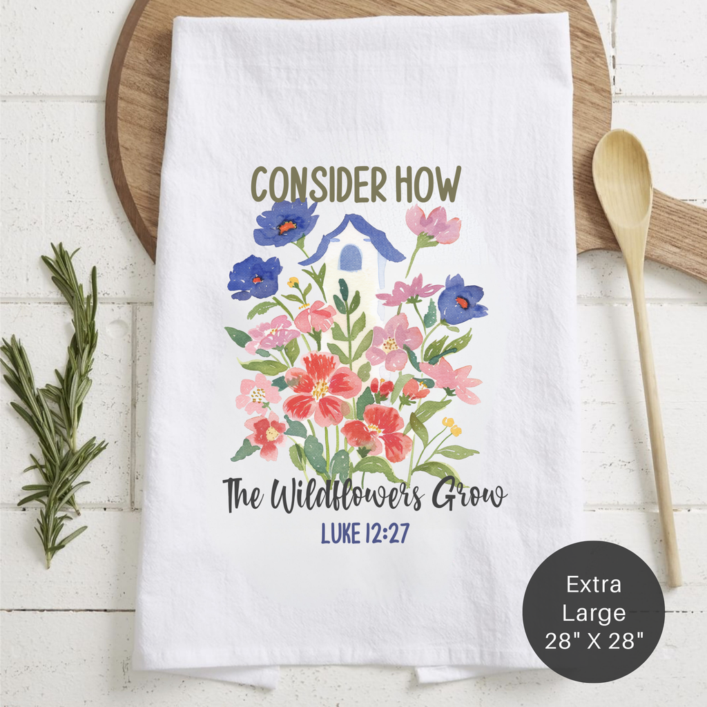 Folded tea towel with bird house floral design and text on a wooden surface.