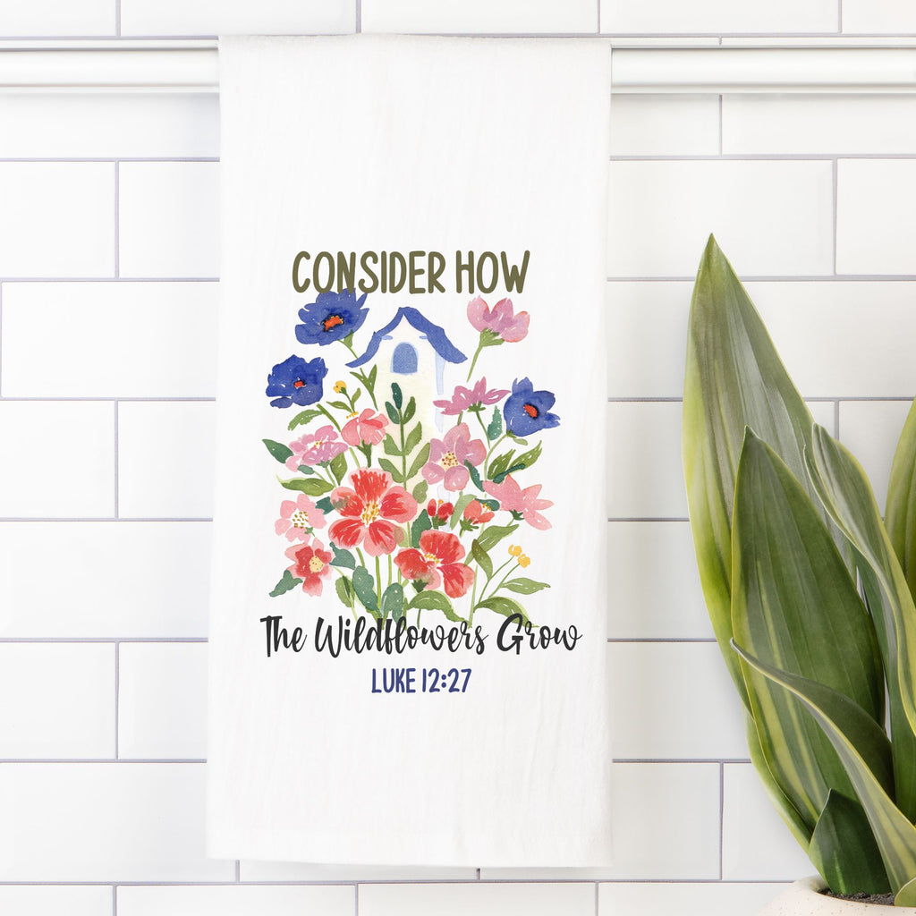 Tea towel with a Floral design and text 'Consider how the wildflowers grow Luke 12:27' on a white tiled background.