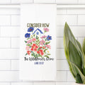 Tea towel with a Floral design and text 'Consider how the wildflowers grow Luke 12:27' on a white tiled background.
