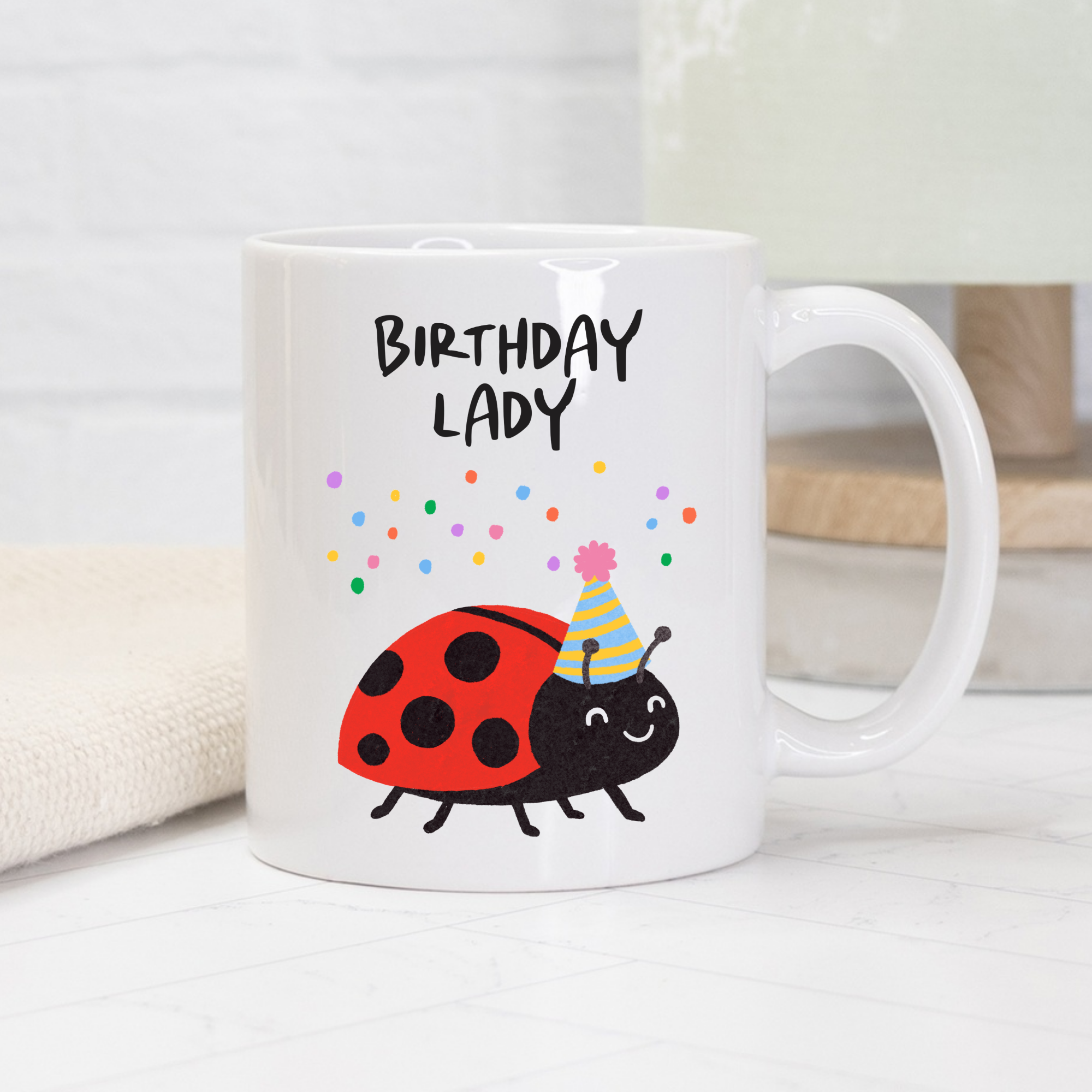 White mug with a cartoon ladybug wearing a party hat and the text 'Birthday Lady' on a white background.