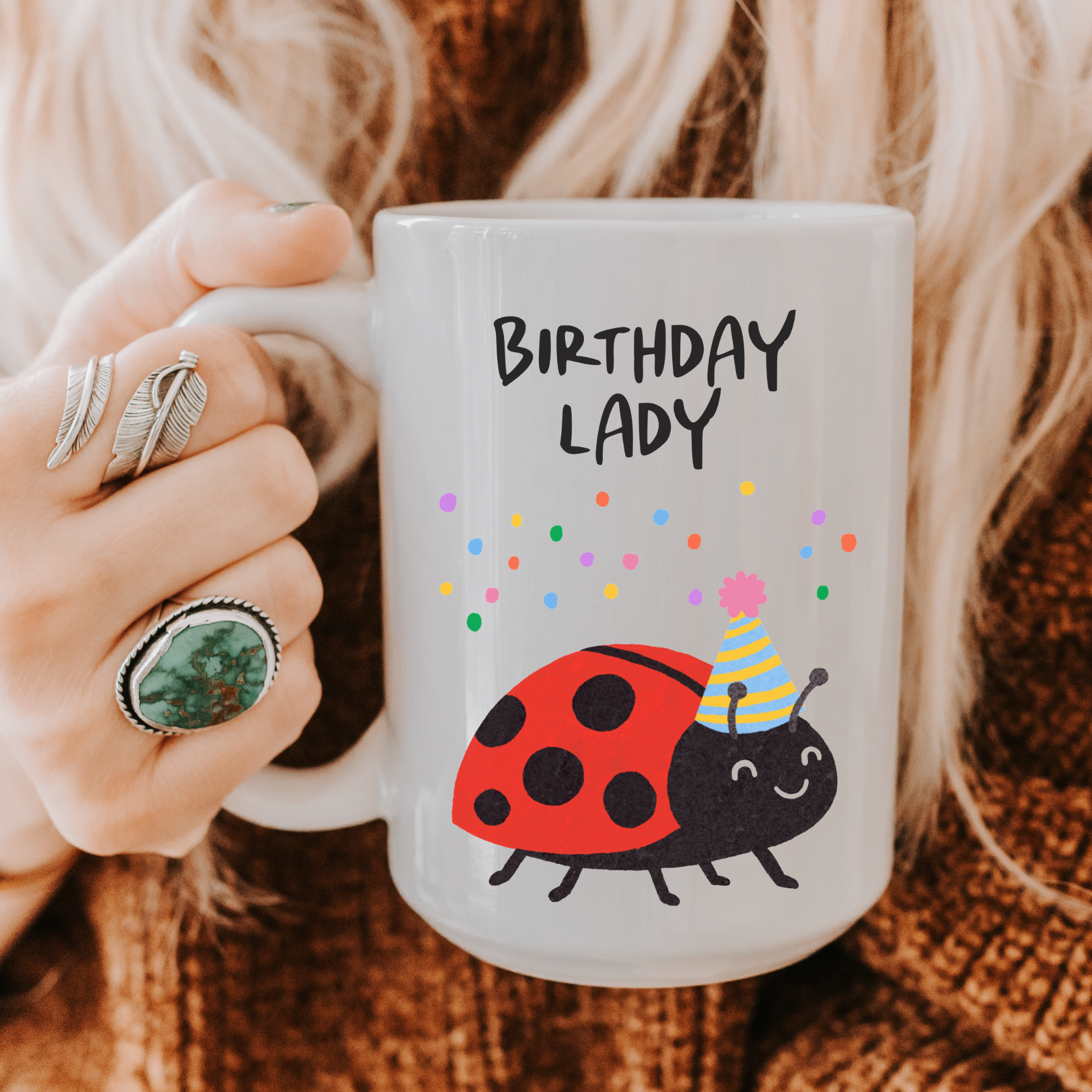 Person holding a mug with 'Birthday Lady' text and ladybug design.