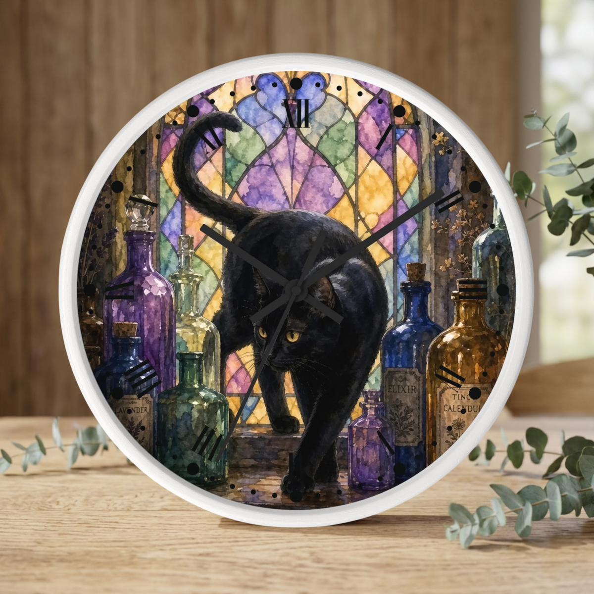 A round wall clock with a white frame sits on a wooden surface. The clock face features an illustration of a black cat in front of a colorful stained-glass window with purple, blue, and yellow tones, surrounded by vintage glass bottles.