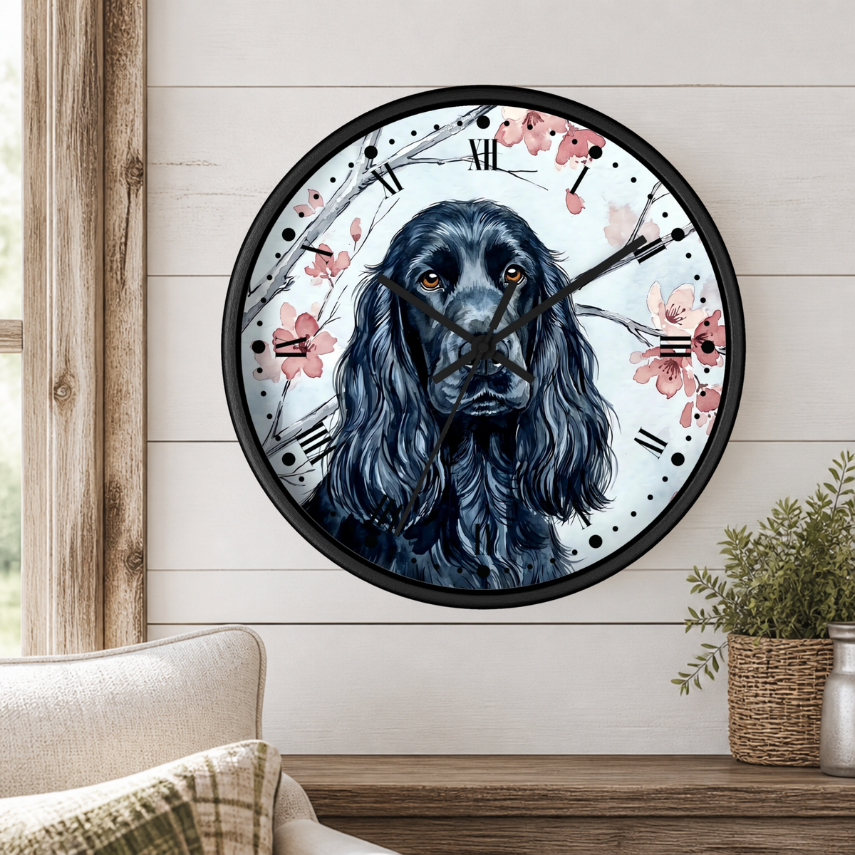 A round wall clock with a black dog portrait and pink cherry blossoms, mounted on a white shiplap wall above a wooden console table with a plant and part of a sofa visible.