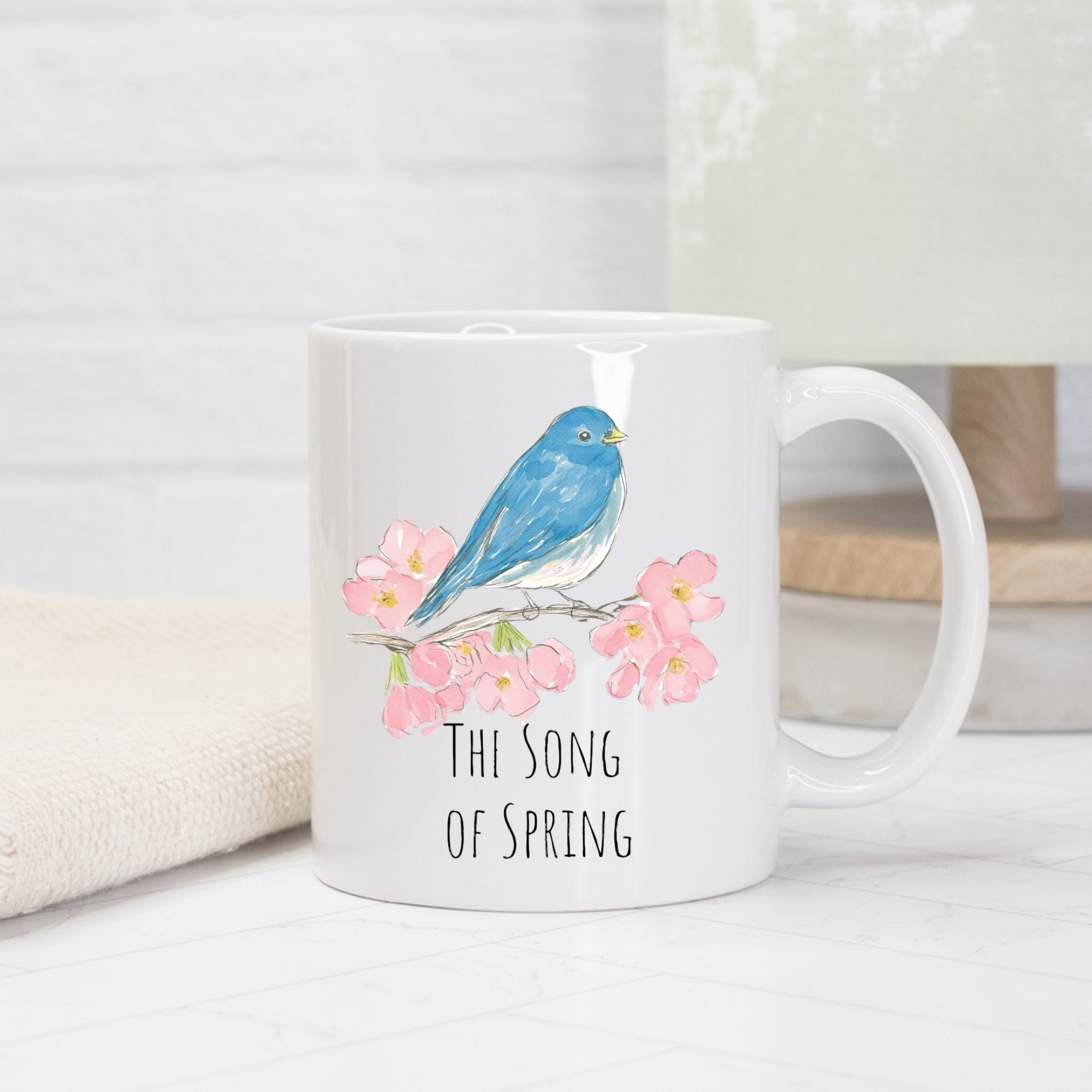 White mug with a blue bird and pink flowers design on a white surface