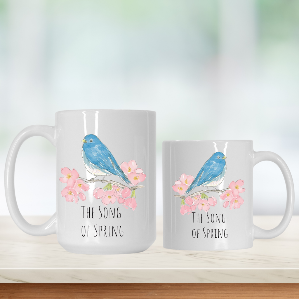 Two mugs with a blue bird and pink flowers design, featuring the text 'The Song of Spring'.