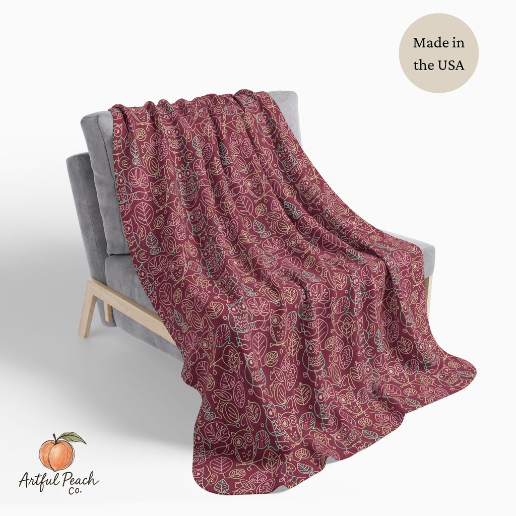 Red patterned blanket draped over a chair with 'Artful Peach Co.' branding and 'Made in the USA' text.