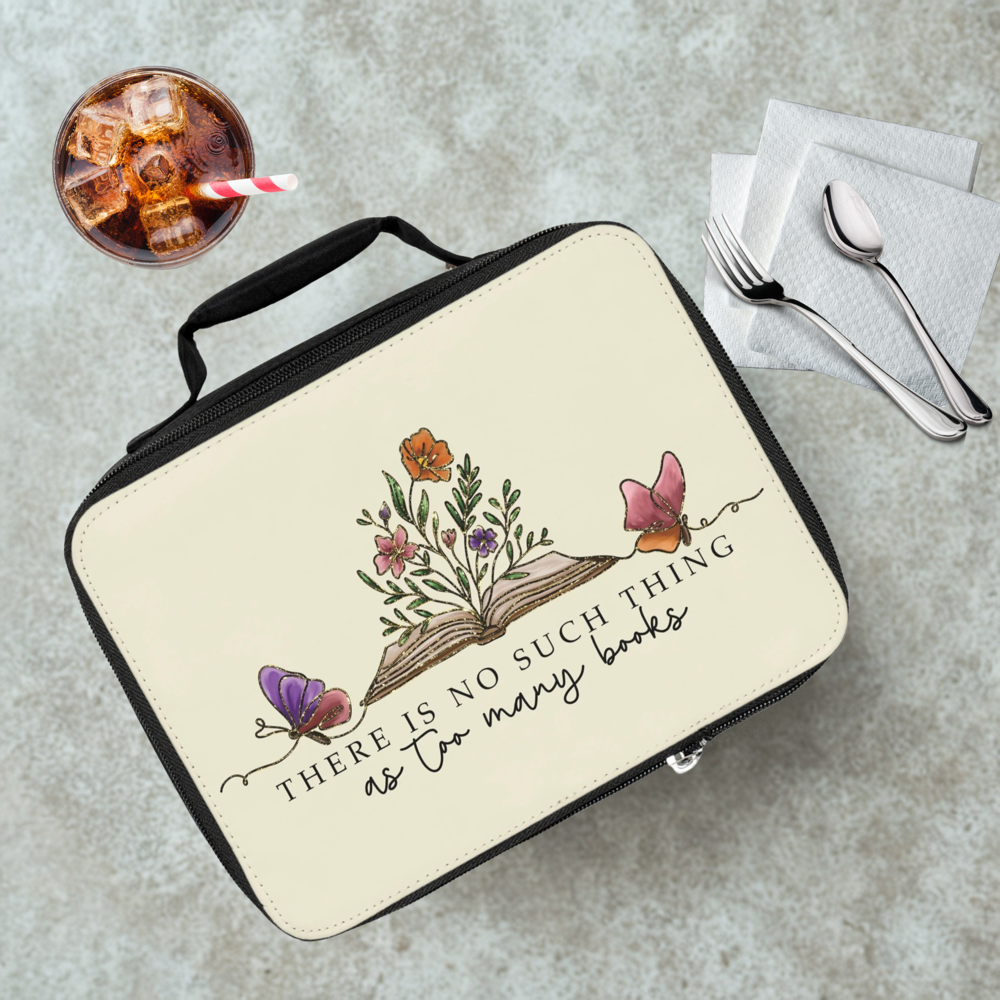 Lunch box with floral design and quote on a cafeteria table with a drink and utensils