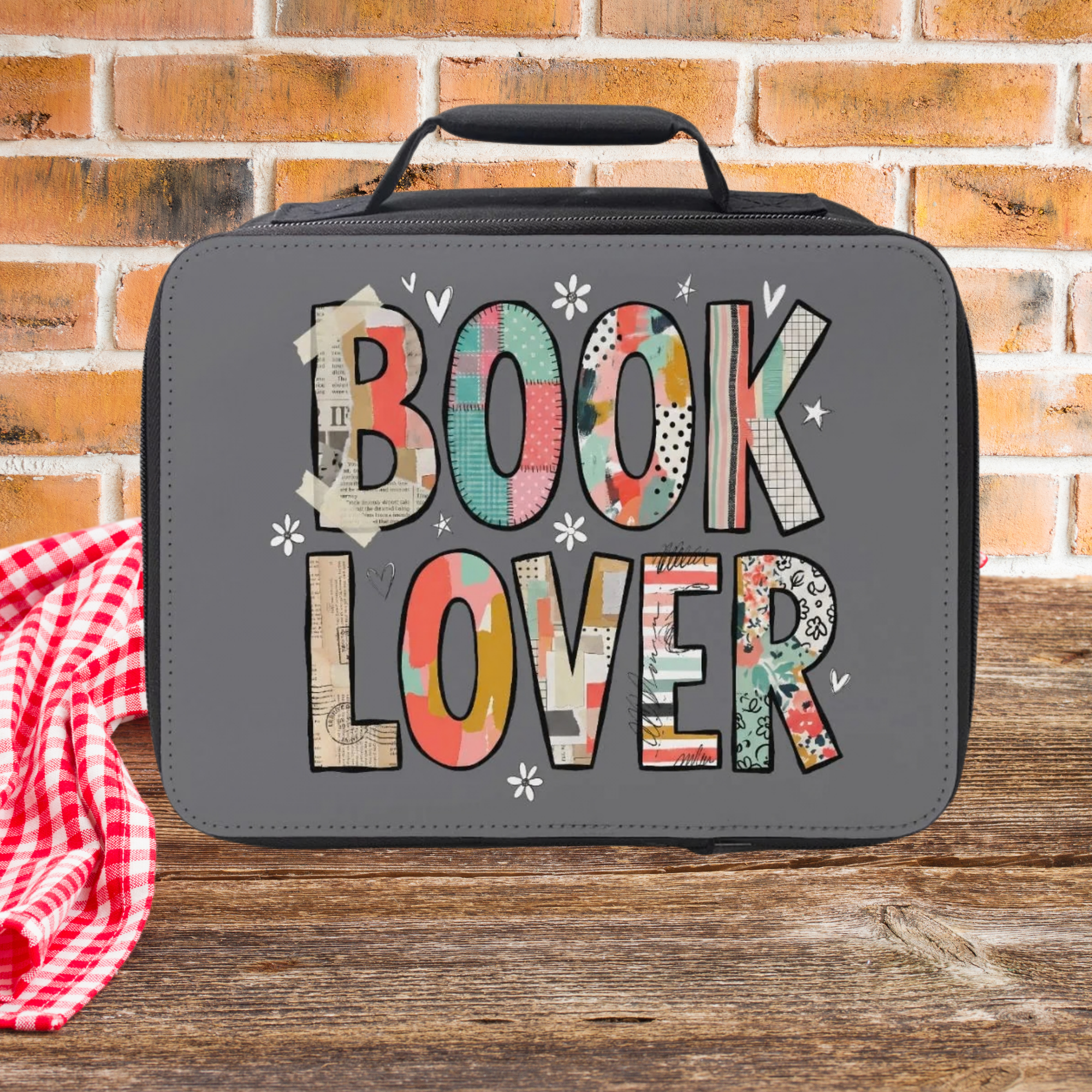 Gray lunch bag with 'BOOK LOVER' text on a wooden surface and brick wall background
