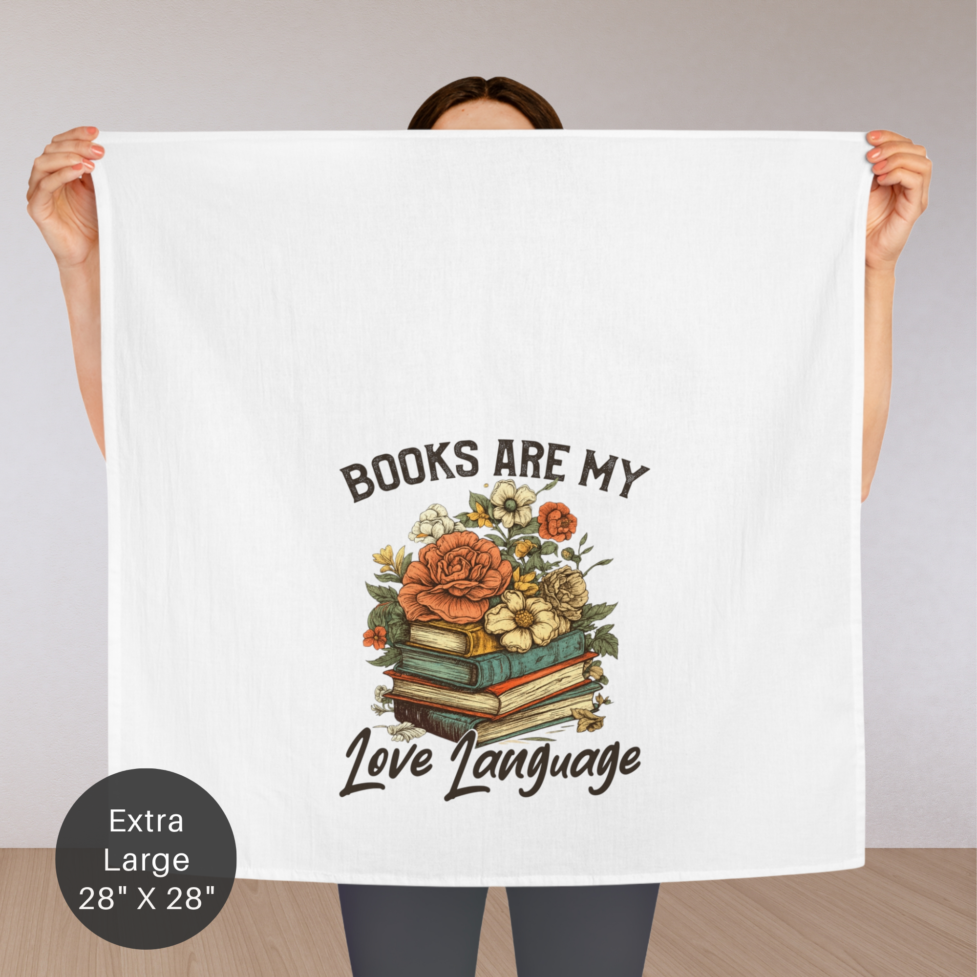 Person holding a an extra large tea towel with a floral design and text on a plain background