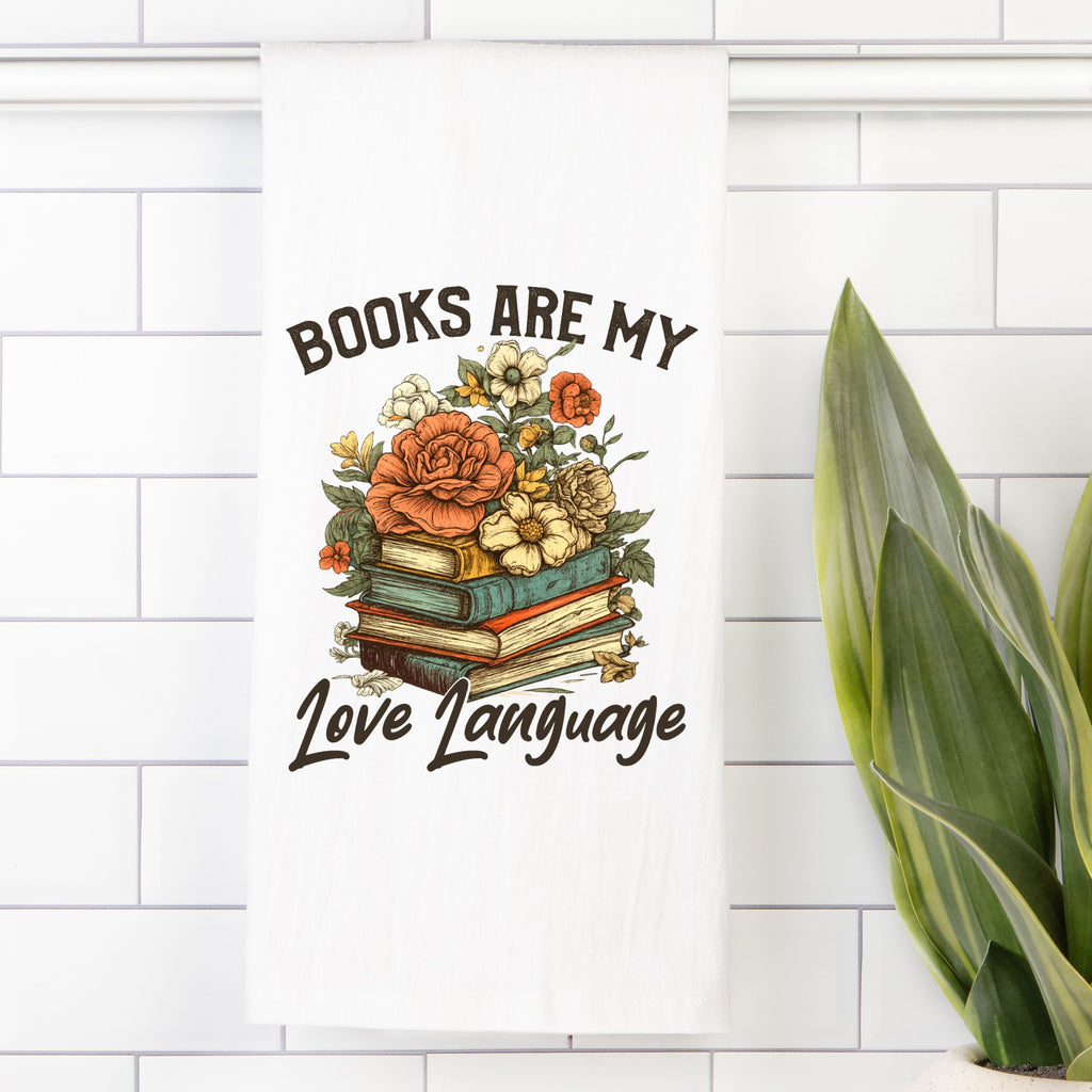 Decorative tea towel with books and flowers on a white tiled wall.