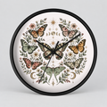 Round wall clock with a black frame and a white face featuring a symmetrical butterfly and floral illustration in muted green, orange, pink, and brown tones.