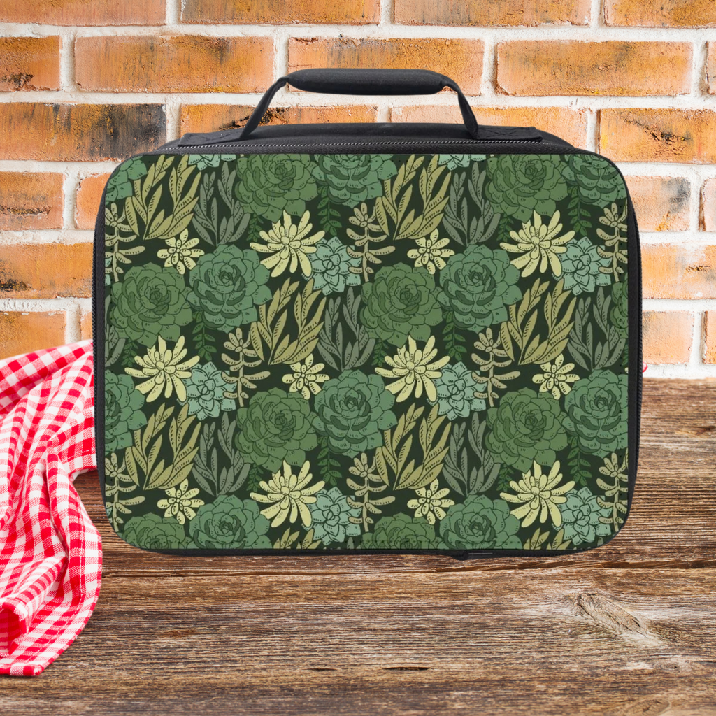 Green floral patterned lunch bag on a wooden picnic table with a brick wall background