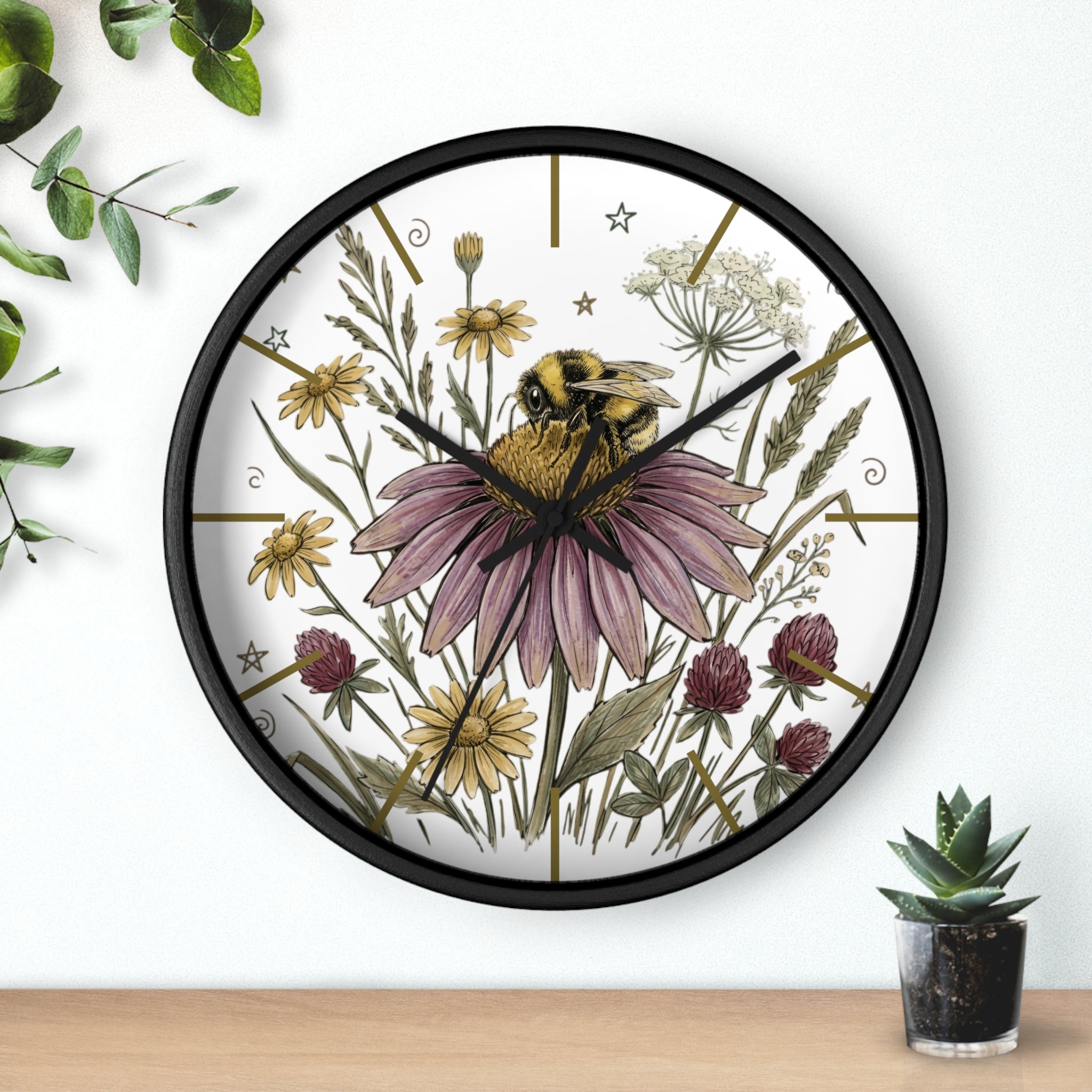 Round black decorative wall clock with a hand drawn bee and flower design on a white background