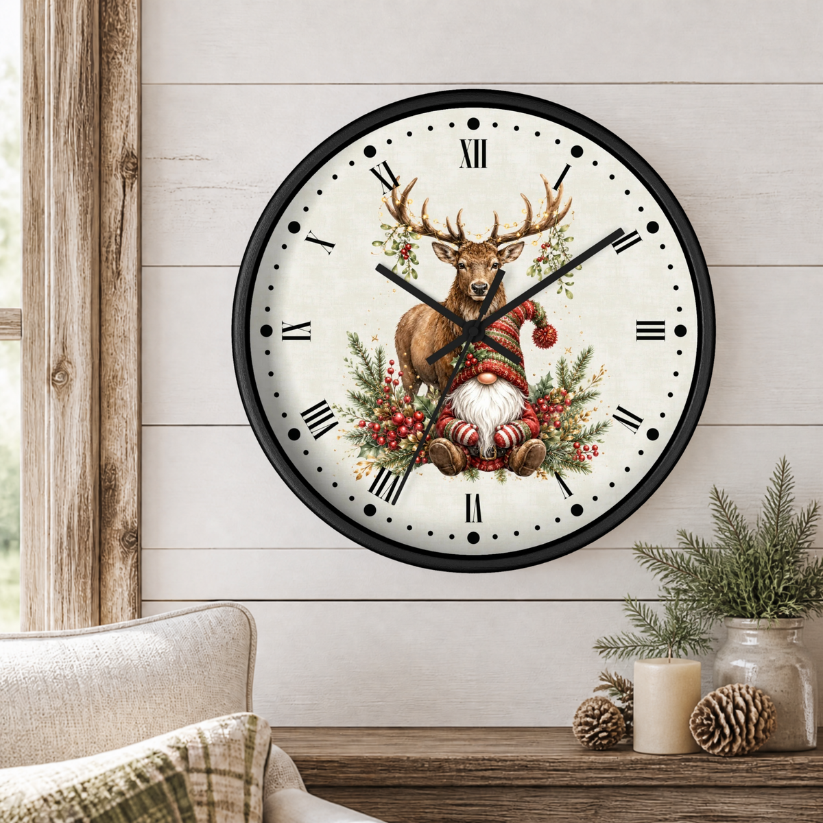 A round wall clock with a black frame and a festive Christmas design featuring a stag with antlers, a Santa-clad gnome, and evergreen branches on the clock face. The clock is mounted on a white shiplap wall above a wooden table with candles and pinecones.