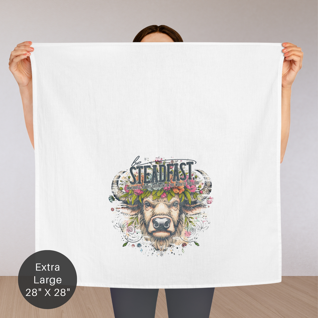 Person holding a extra large white tea towel with a colorful design of a buffalo and the word 'Steadfast' on a plain background.
