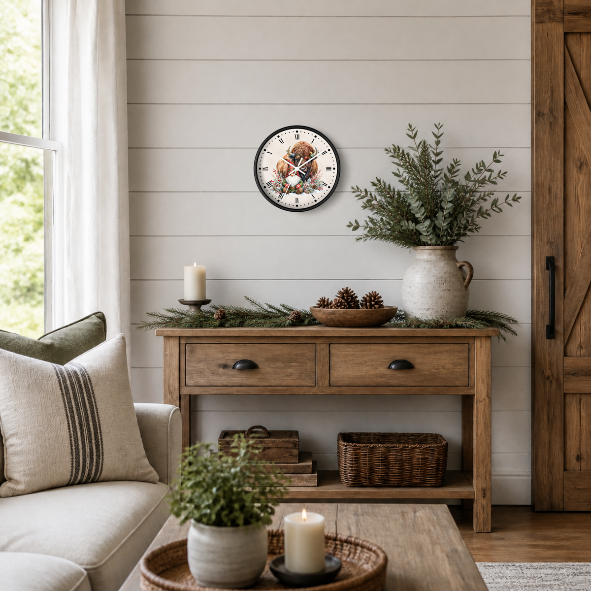 A round wall clock featuring a festive gnome and bison illustration, styled in a cozy, rustic living room setting above a wooden console table with holiday greenery and candles. 