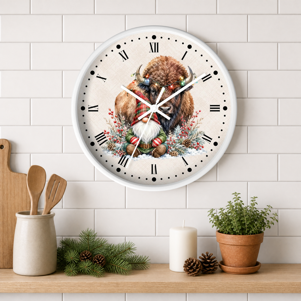 A round wall clock with a white frame hangs on a white subway tile wall above a wooden shelf. The clock face features a festive illustration of a bison surrounded by holiday greenery and ornaments.