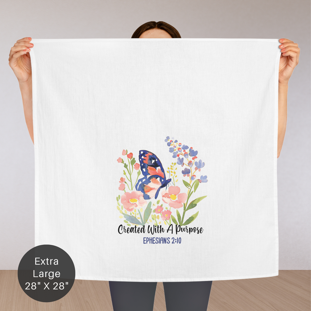 Person holding an extra large white tea towel with a colorful butterfly and floral design, featuring the text 'Created With A Purpose Ephesians 2:10'.