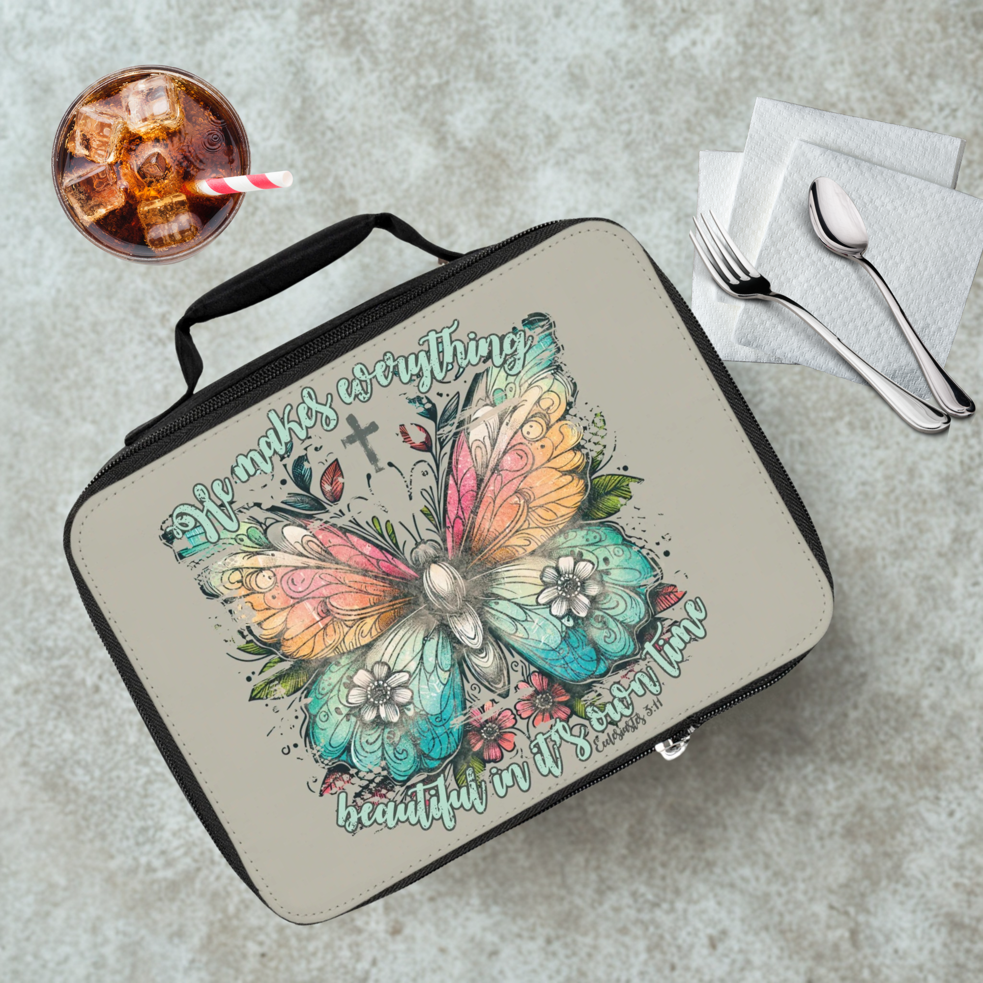 Lunch bag with butterfly design and text on a cafeteria table with a drink and utensils.