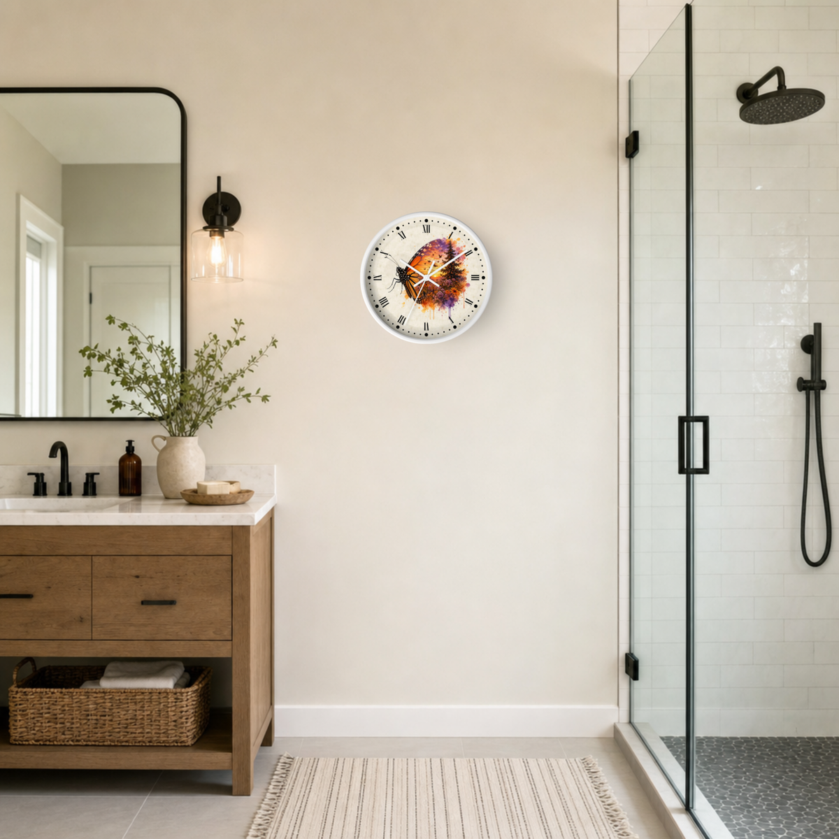 A round wall clock with a colorful butterfly or floral face design hangs on a beige wall in a modern bathroom setting with a wooden vanity, mirror, and glass shower enclosure.