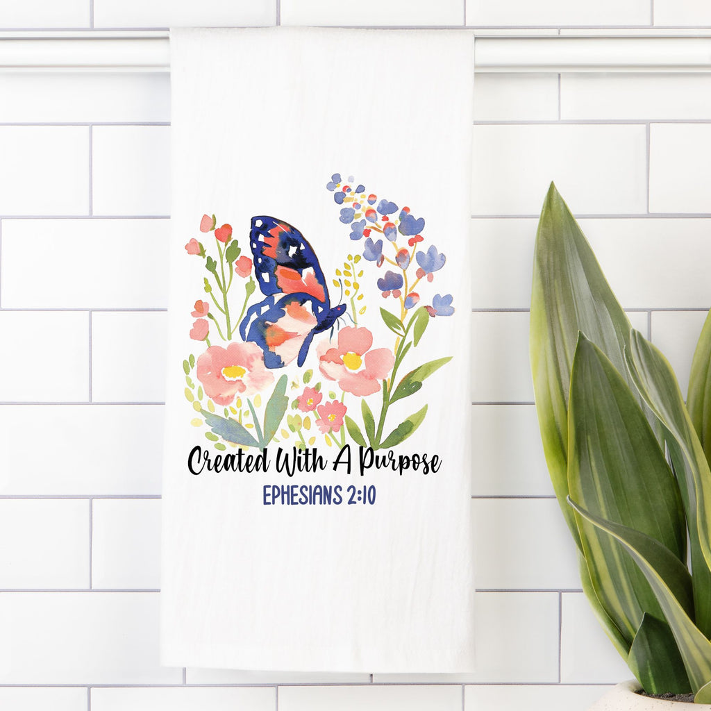 Decorative tea towel with a butterfly and flowers on a white tiled wall.