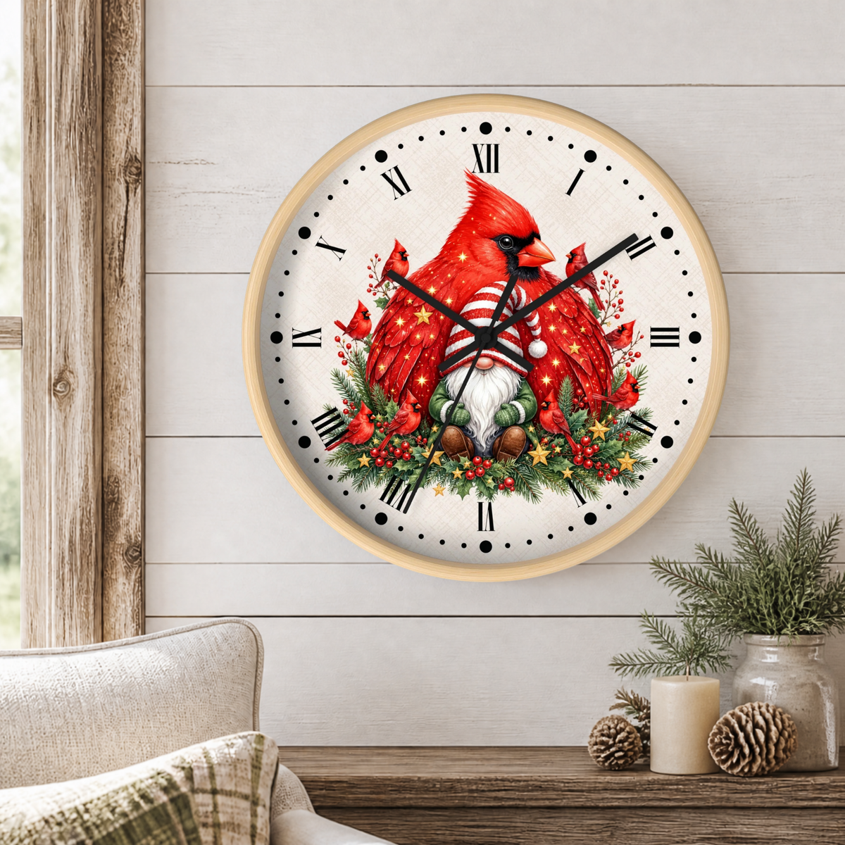 A round wall clock with a light wood frame hangs on a white shiplap wall above a wooden table. The clock face features a festive design with a red cardinal, green holly leaves, pinecones, and a small white gnome.
