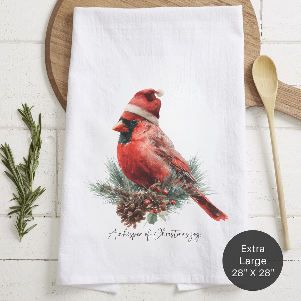 White towel with a red cardinal bird wearing a Santa hat on a wooden surface.