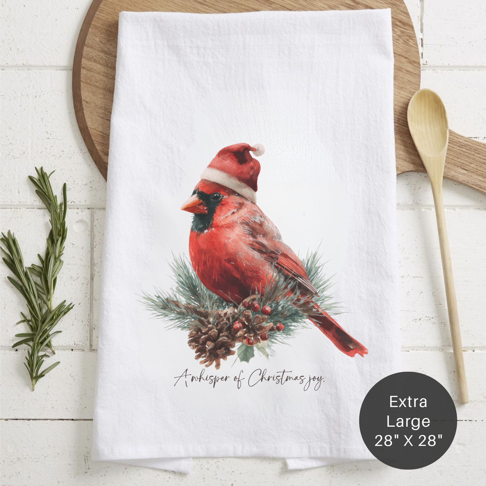 White towel with a red cardinal bird wearing a Santa hat on a wooden surface.