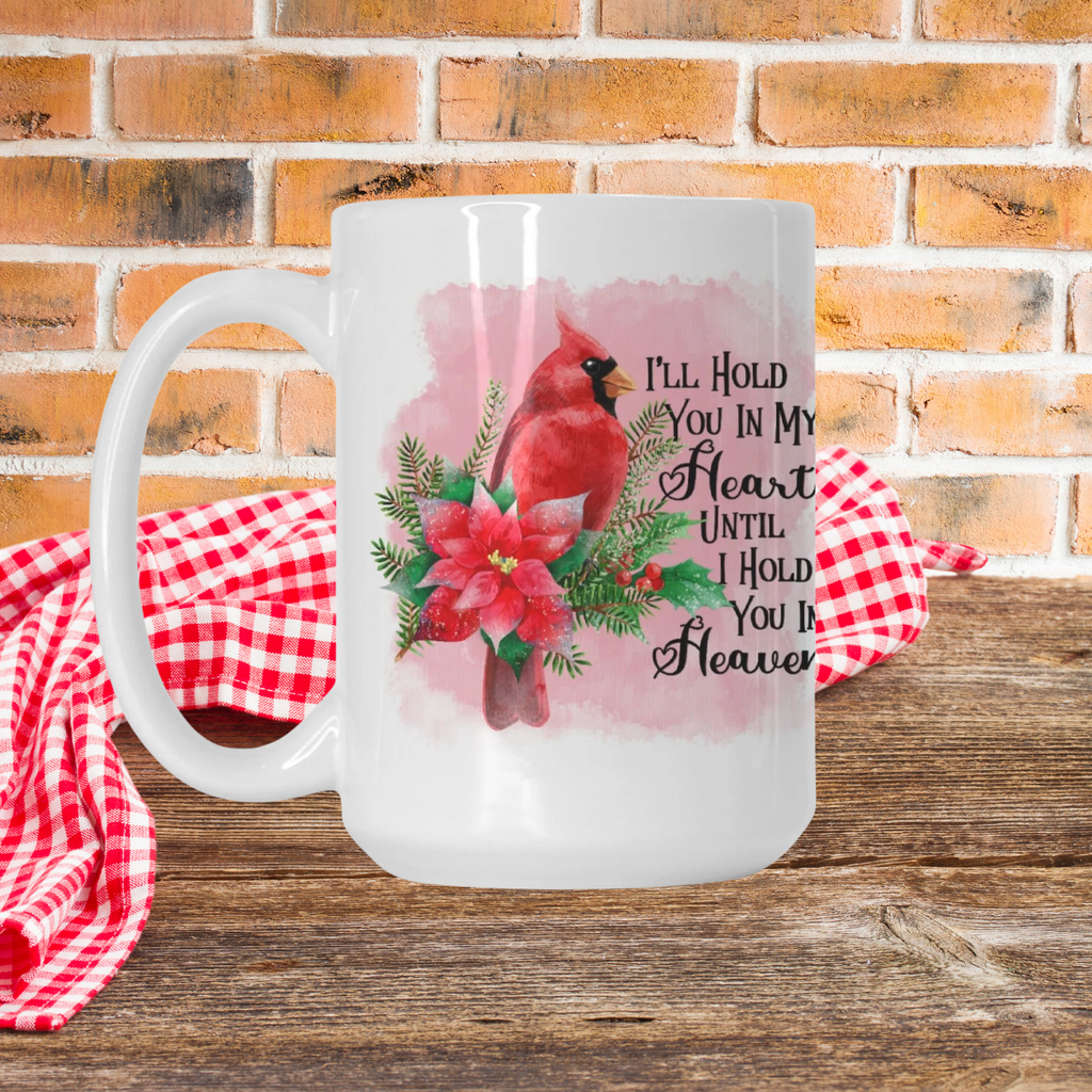 White mug with a red cardinal and floral design on a wooden surface with a brick wall background