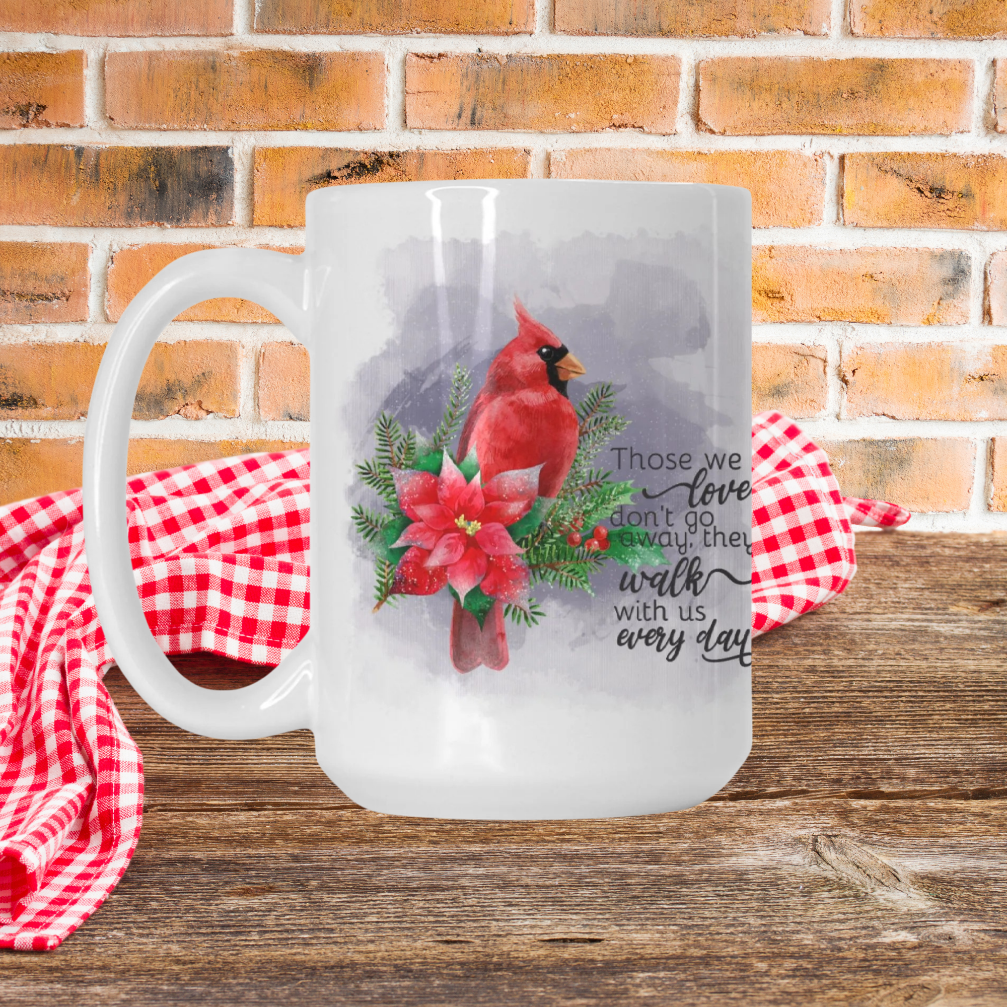 Frosted mug with a red cardinal and floral design on a wooden surface with a brick wall background.
