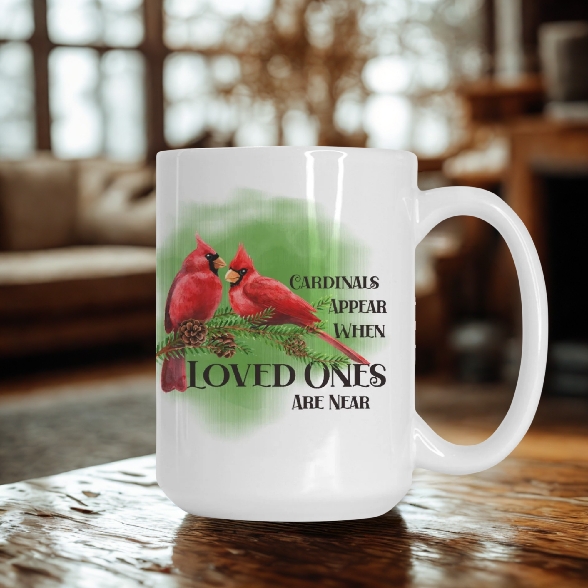 White mug with red cardinals and text on a wooden table in a cozy room.