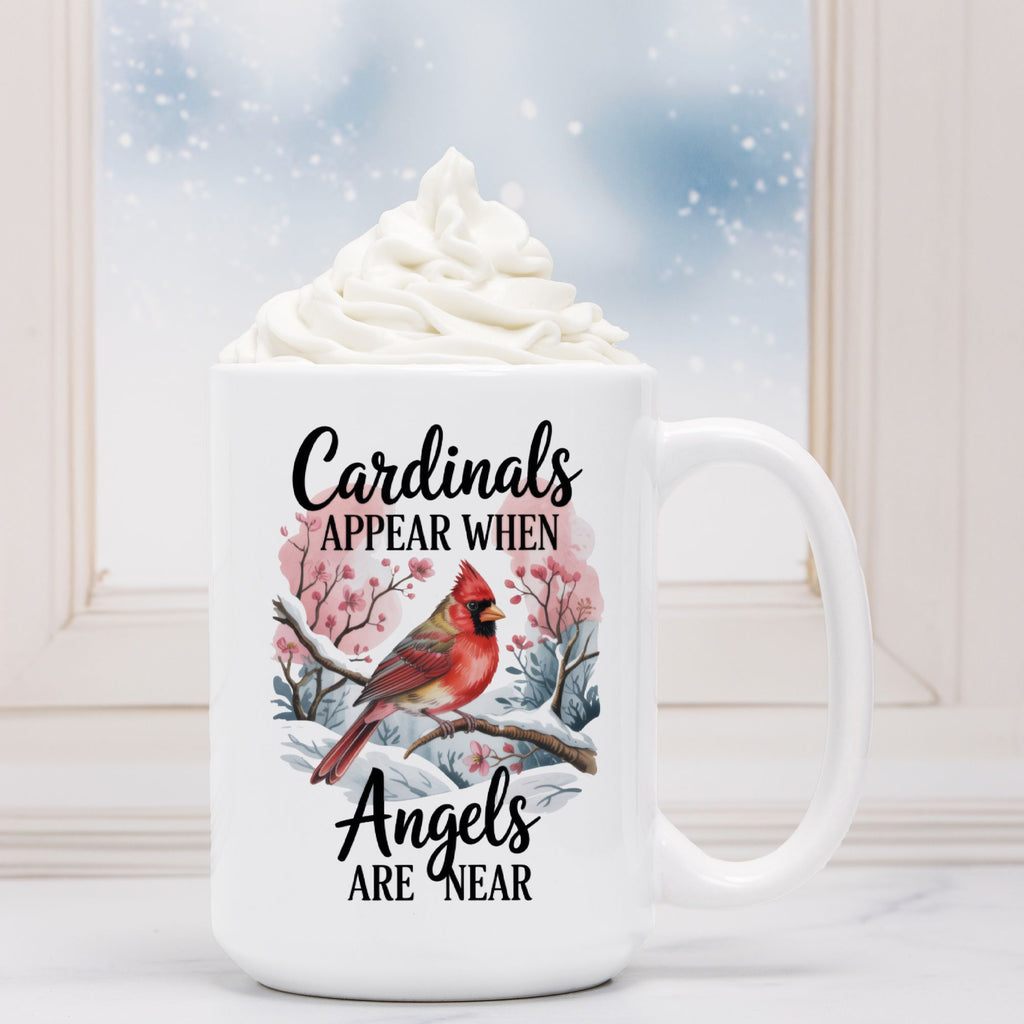 White mug with cardinal design and text 'Cardinals appear when angels are near' on a snowy background.