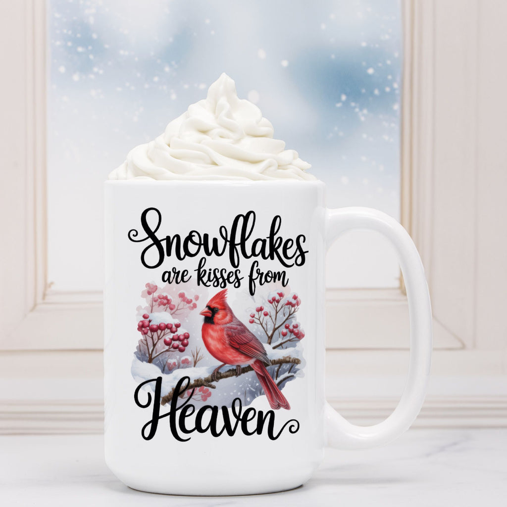 White mug with a cardinal design and text 'Snowflakes are kisses from Heaven' against a snowy background.