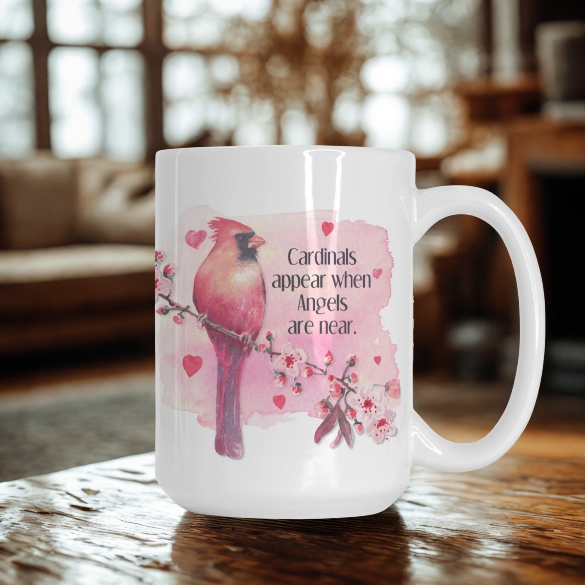 White mug with pink cardinal design and text on a wooden surface