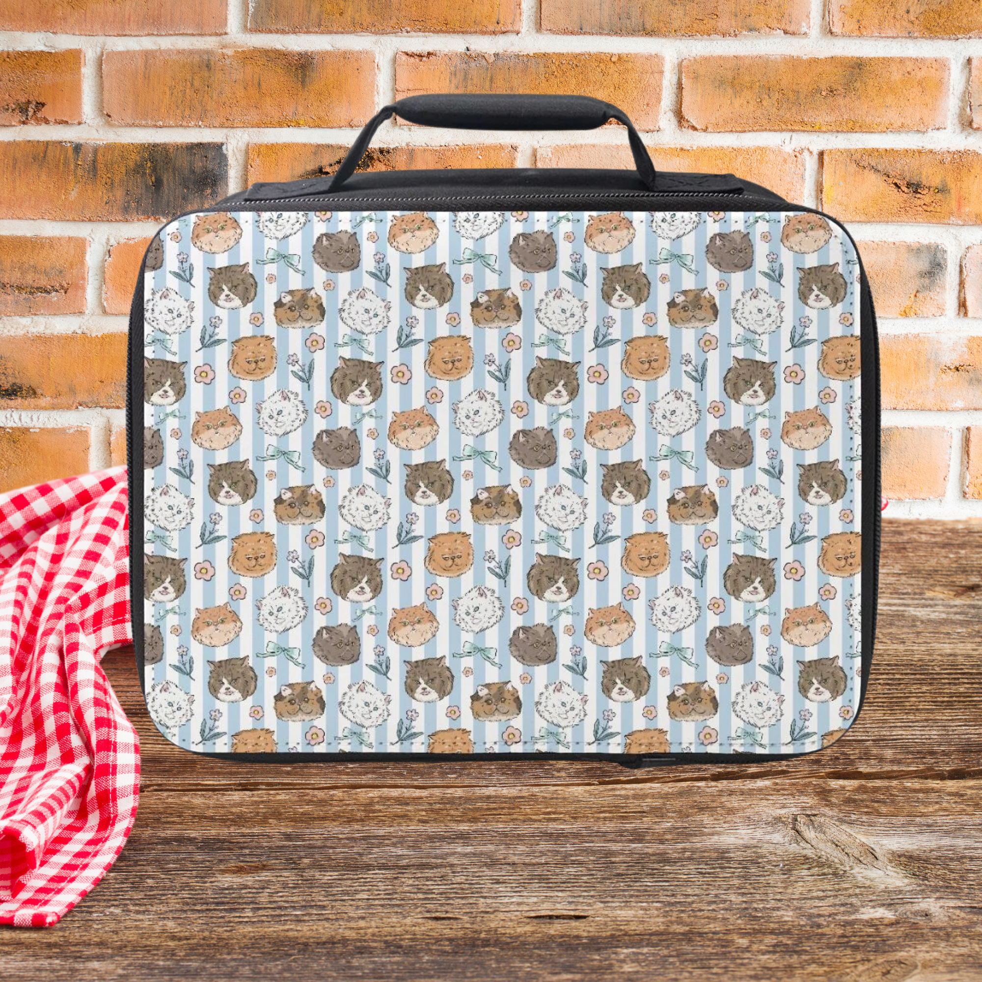 Lunch bag with hand drawn cat pattern on a wooden picnic table and brick wall background