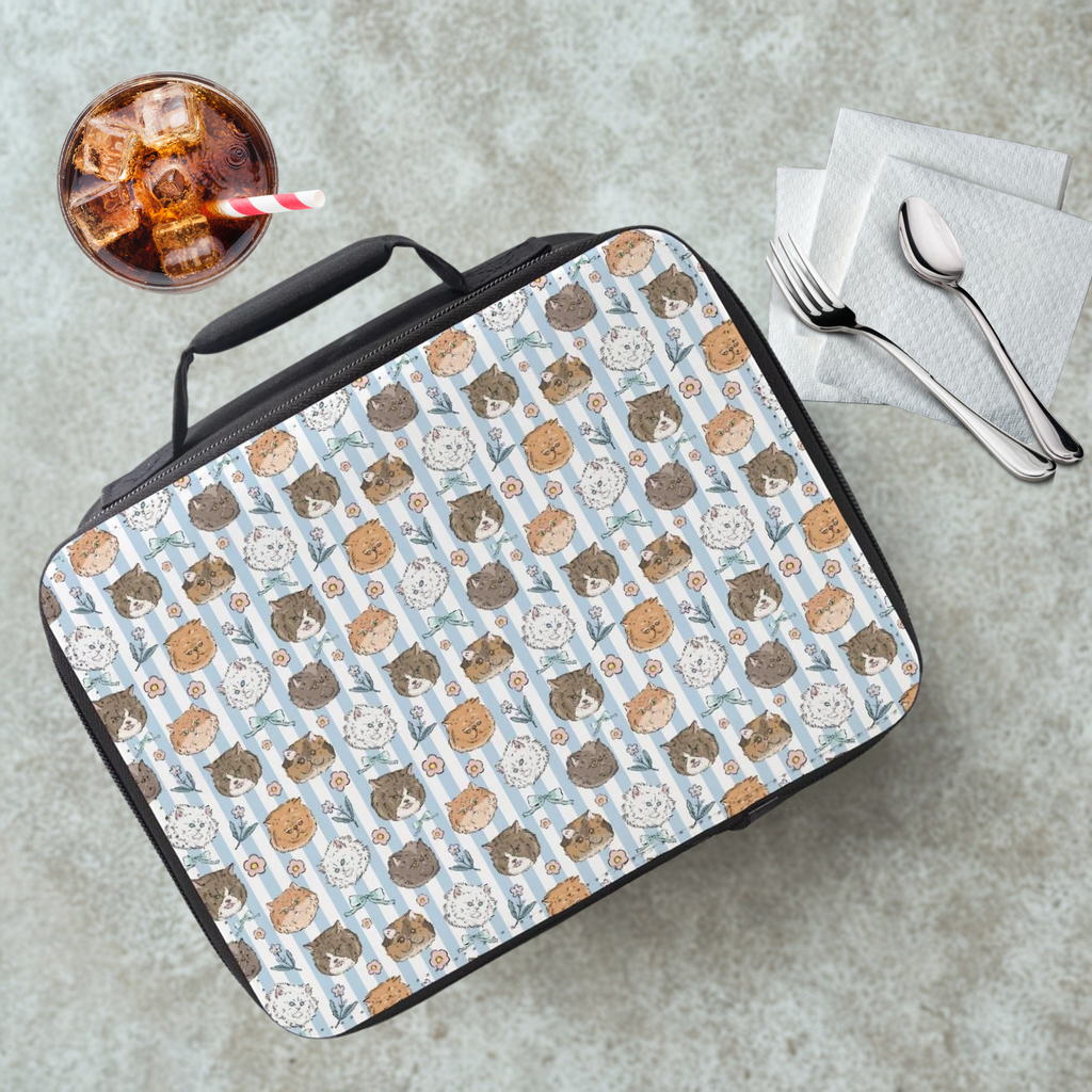 Lunch bag with a hand drawn cat pattern on a cafeteria table with a drink and utensils.