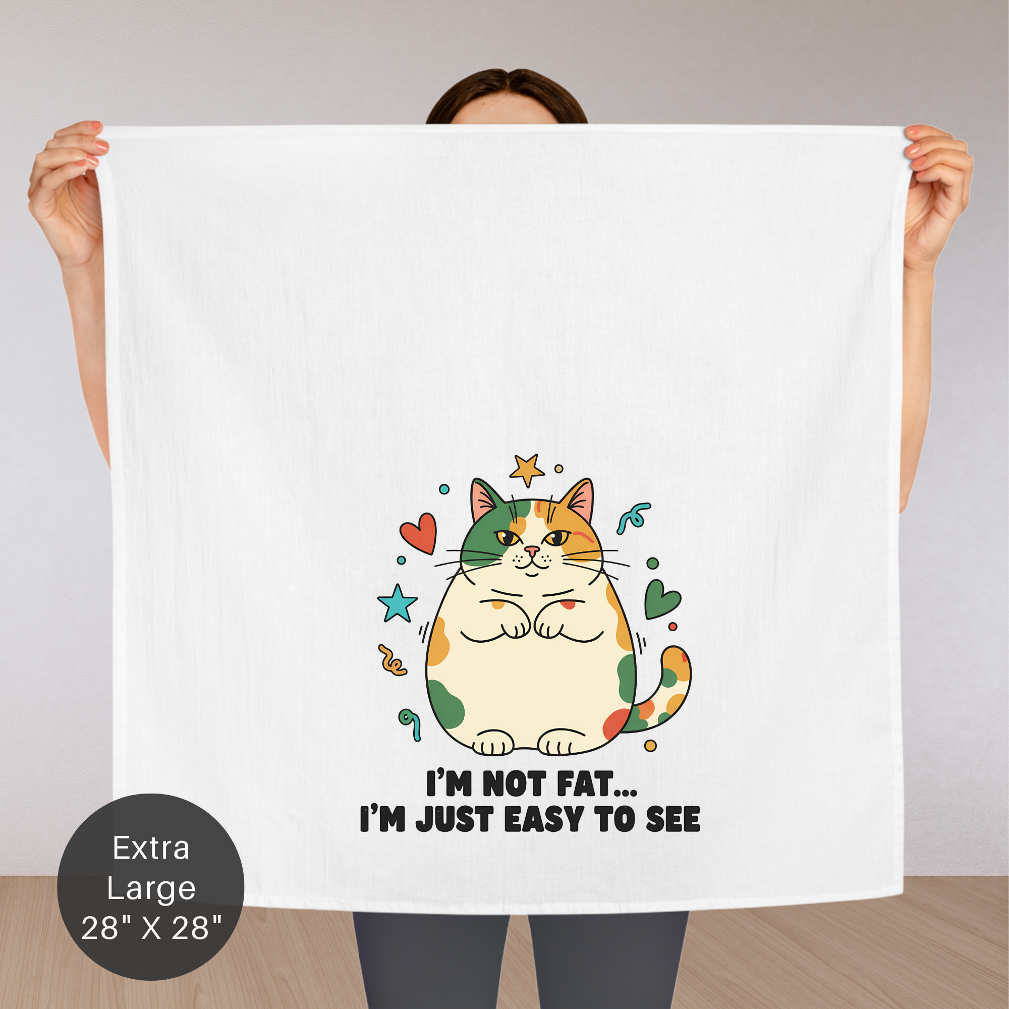 Person holding an extra large tea towel  with a cat illustration and text.