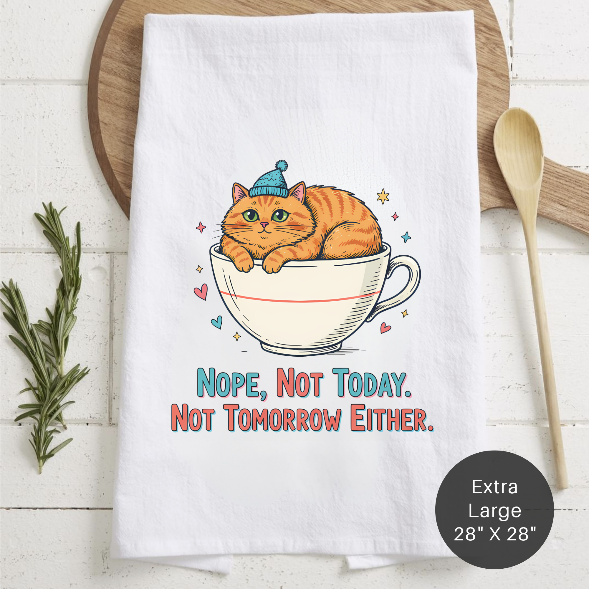 White tea towel with a cat in a teacup design and text 'Nope, Not Today. Not Tomorrow Either.' on a wooden surface.