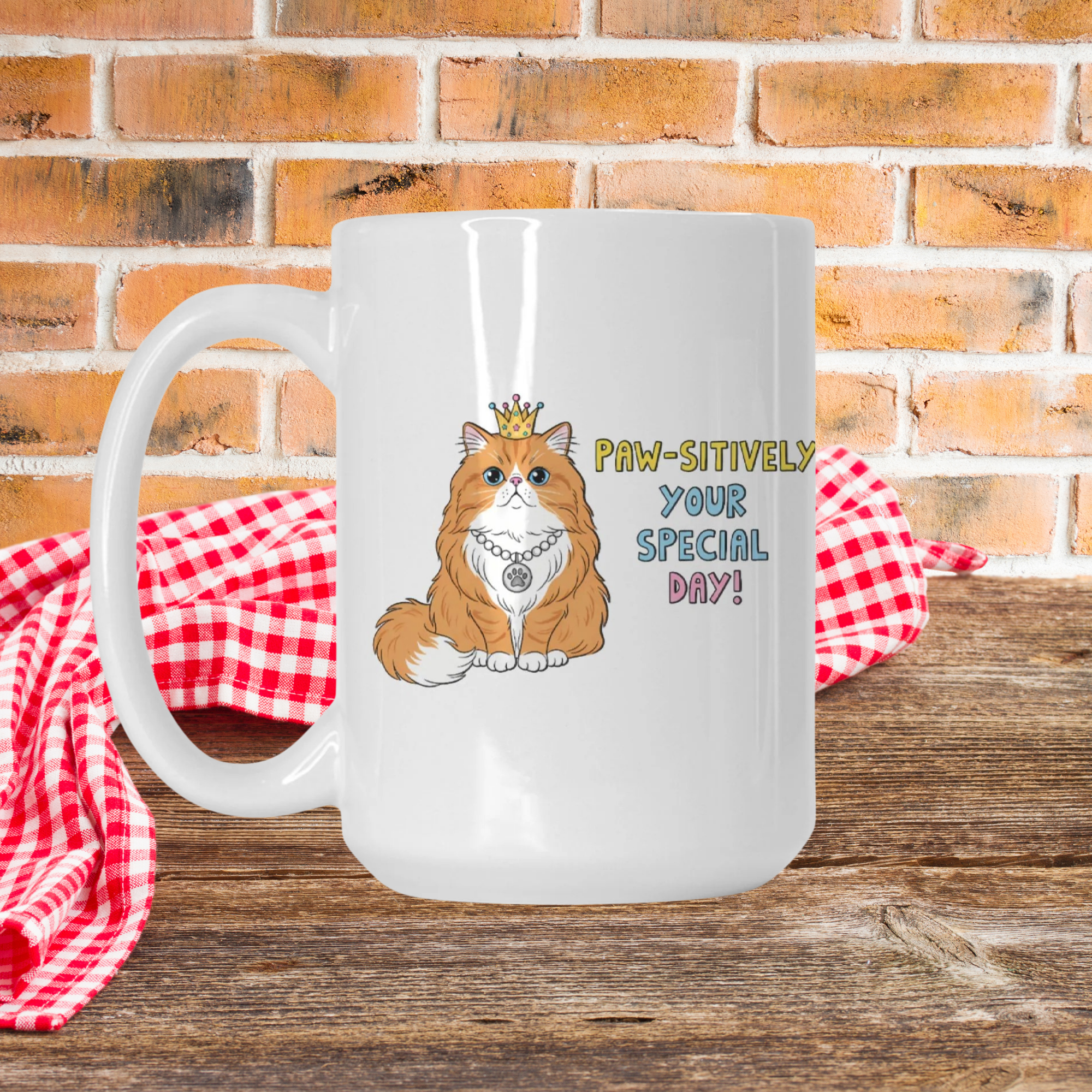 White mug with a cat illustration and text on a wooden surface with a red checkered cloth and brick wall background.