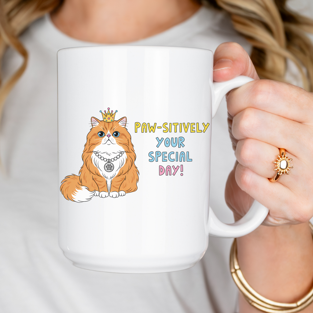 Person holding a mug with a cat illustration and text 'PAW-sitively Your Special Day!'