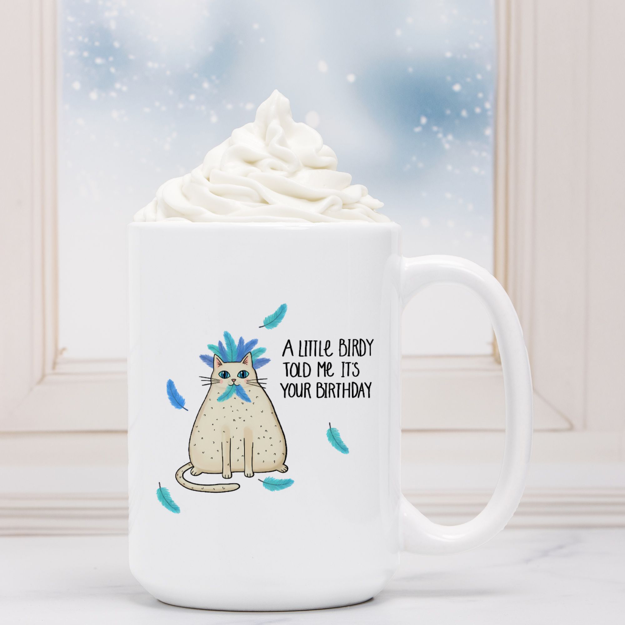 White mug with a cat illustration and text, filled with hot chocolate and whipped cream.