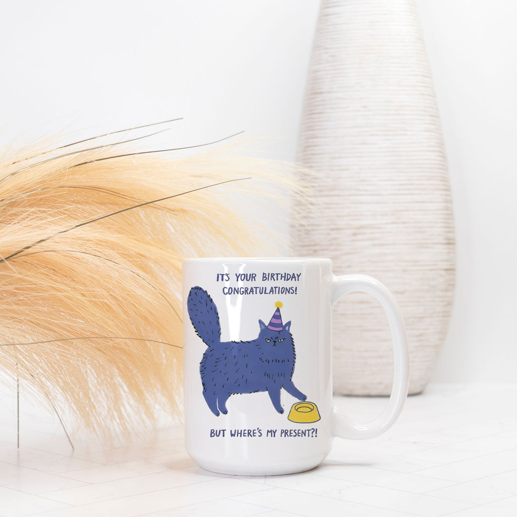 White mug with a blue cat illustration and text on a white background