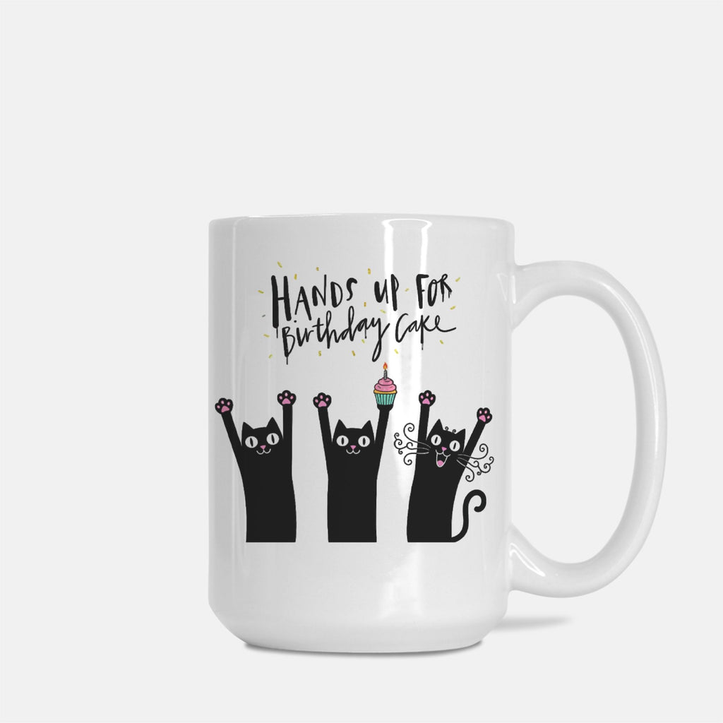 White mug with black cat illustrations and text 'Hands up for Birthday Cake' on a white background