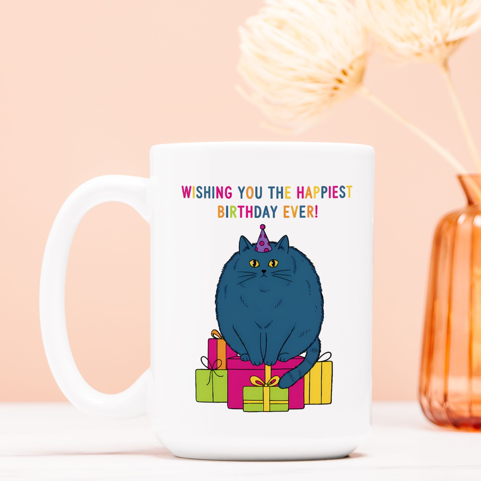 White mug with a cat illustration and birthday text on a light pink background