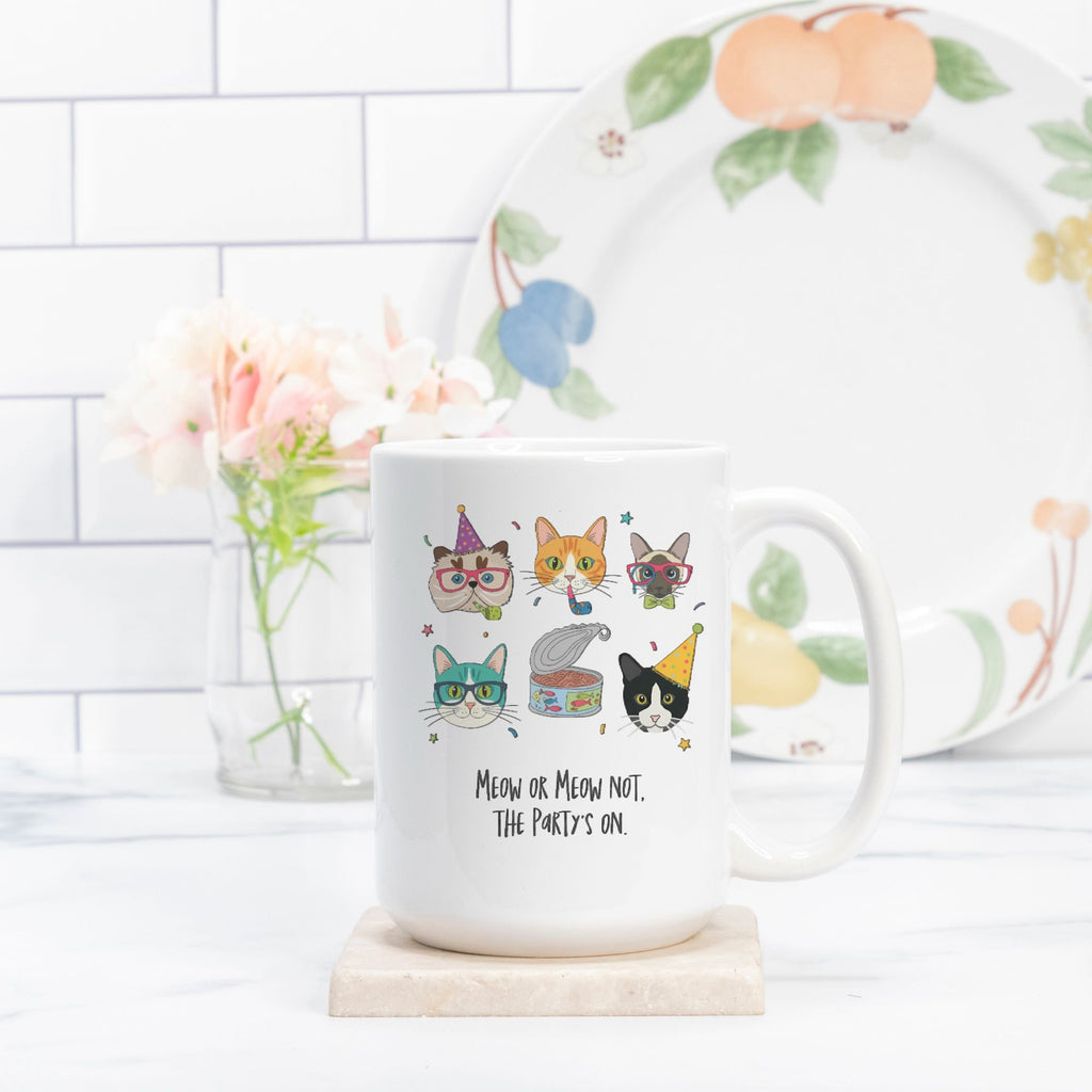 White mug with cat-themed design and text on a white surface with a decorative plate in the background.