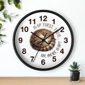 Round black wall clock with a cat illustration and humorous text on a white background