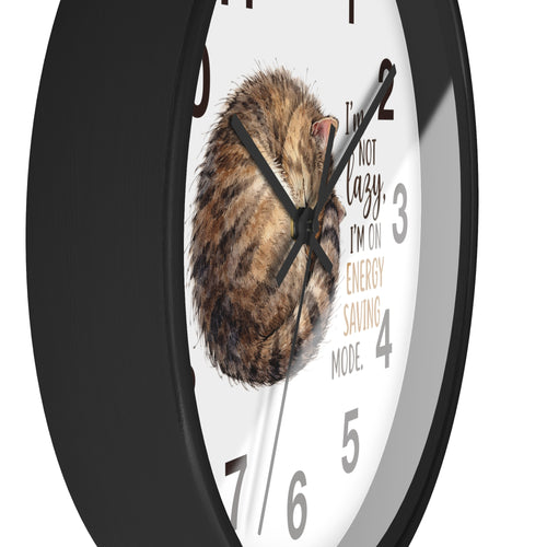 Side view of a round black wall clock with a cat illustration and humorous text on a white background