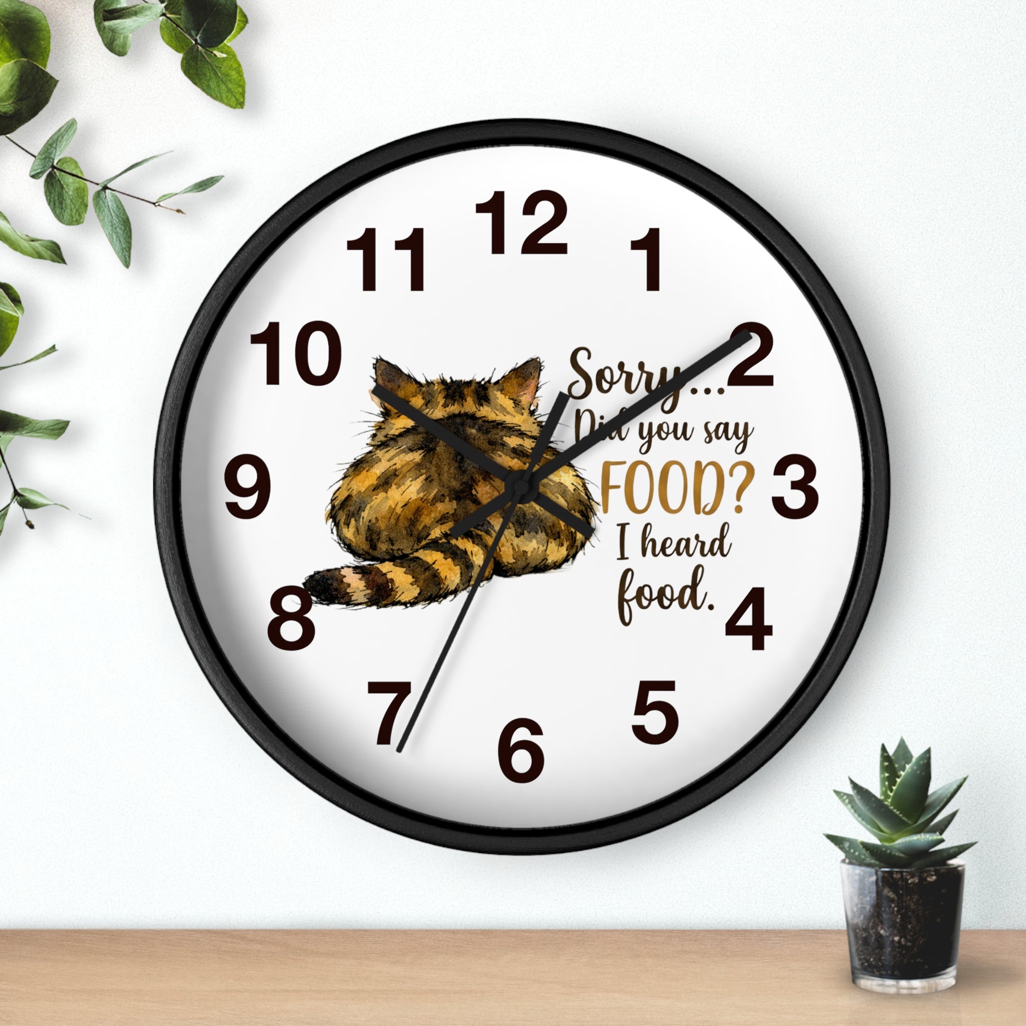 Round black wall clock with a cat illustration and humorous text on a white background