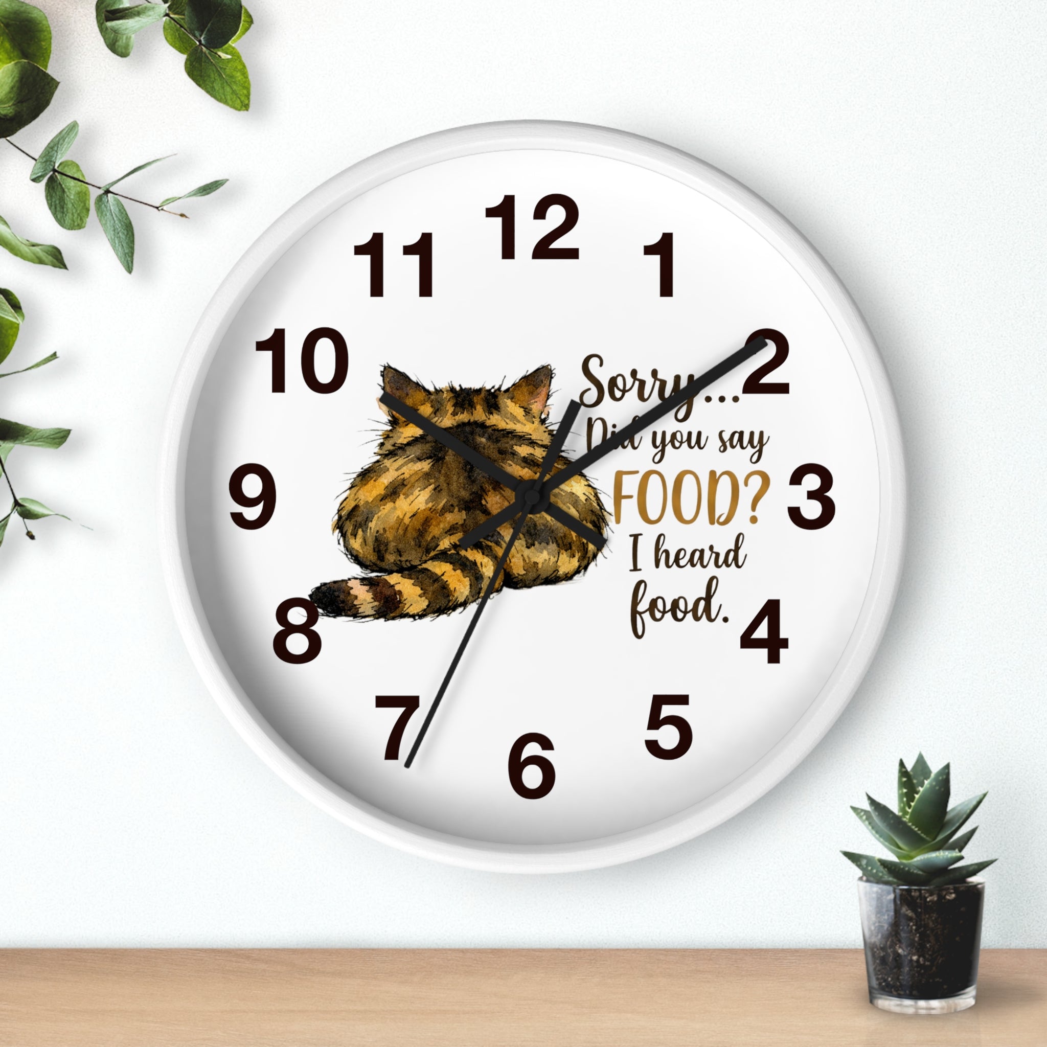 Round white wall clock with a cat illustration and humorous text on a white background