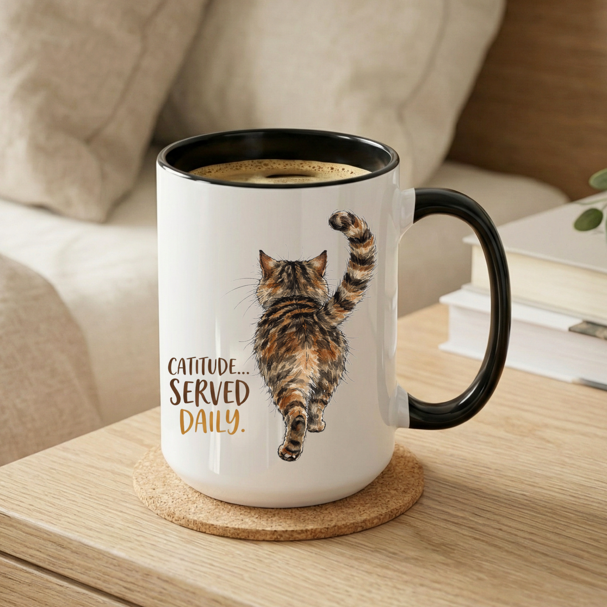 White mug with black handle and a cat illustration with 'Catitude... Served Daily.' text on a wooden surface.